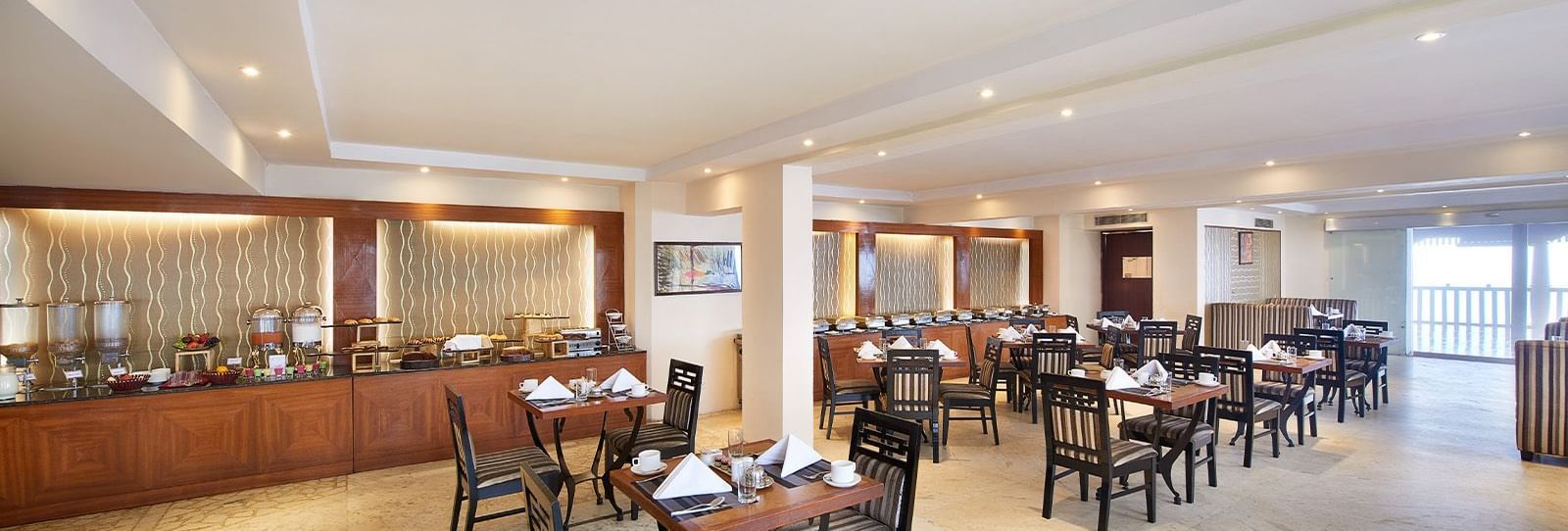 Well-lit interior of Season restaurant with the buffet arrangement in the backdrop at Accord Highland Ooty